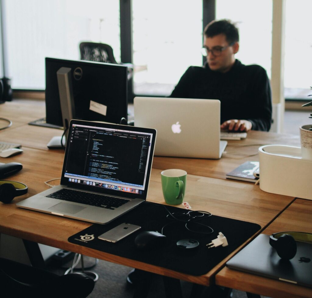 A web developer working on code in a modern office setting with multiple devices.
